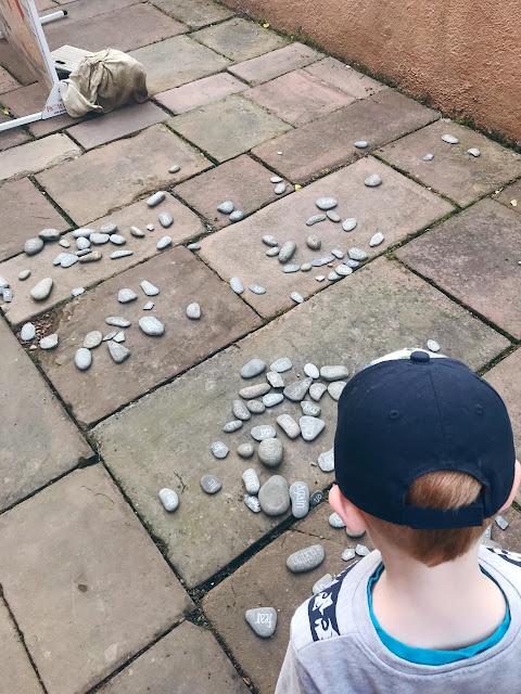 Little boy looking a pebbles with words written on them