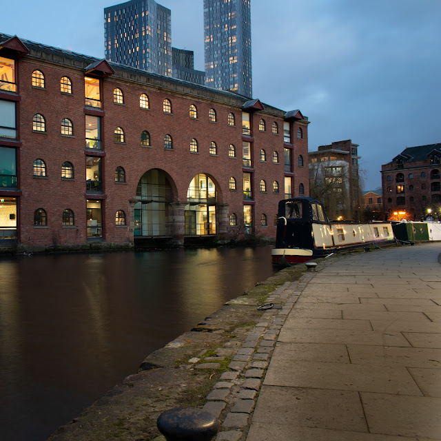 Canal with warehouse lit at twilight and houseboat