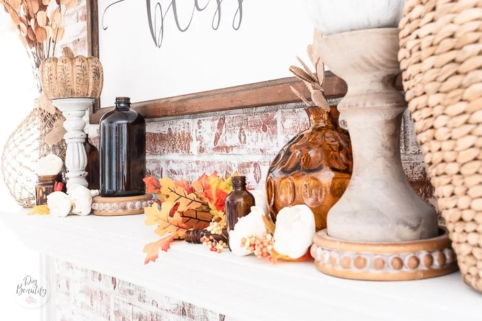 mantel with fall leaves, amber bottles, wood pumpkins and candlesticks