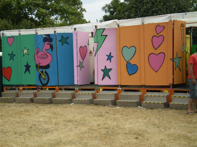 row of brightly painted compost toilets at a festival