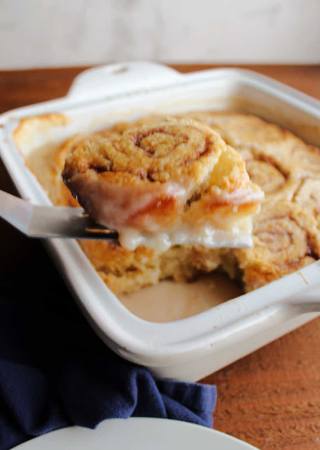 This yummy breakfast recipe is part biscuit like cinnamon rolls and part self saucing pudding cake. It has a gooey sauce that acts almost like a frosting that forms under the rolls. Enjoy them hot for the best breakfast experience. spatula lifting butter roll out of pan with vanilla pudding mixture on bottom