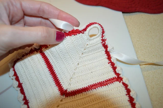 Hand holding red and white crocheted pot holder