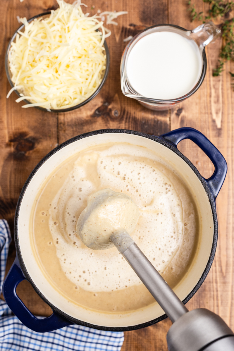 Overhead photo of blending Easy Cauliflower Cheese Soup in a large blue soup pot.