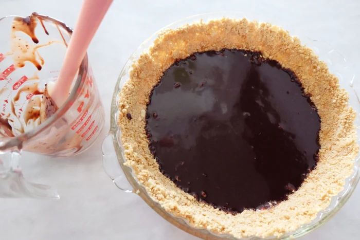 pouring chocolate layer on bottom of pie crust