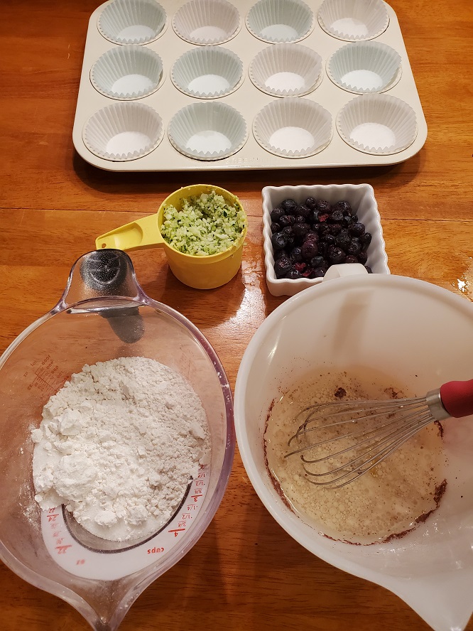 these are all the ingredients to make muffins with zucchini and blueberries and a muffin pan