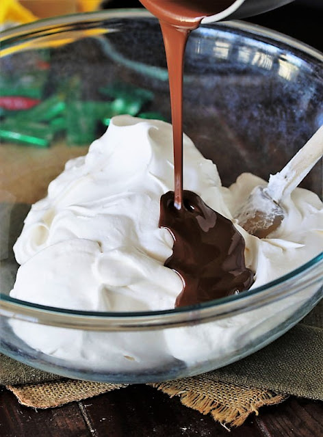 Pouring Melted Andes Mints Into Cool Whip to Make No-Bake Mint Chocolate Chip Pie Image