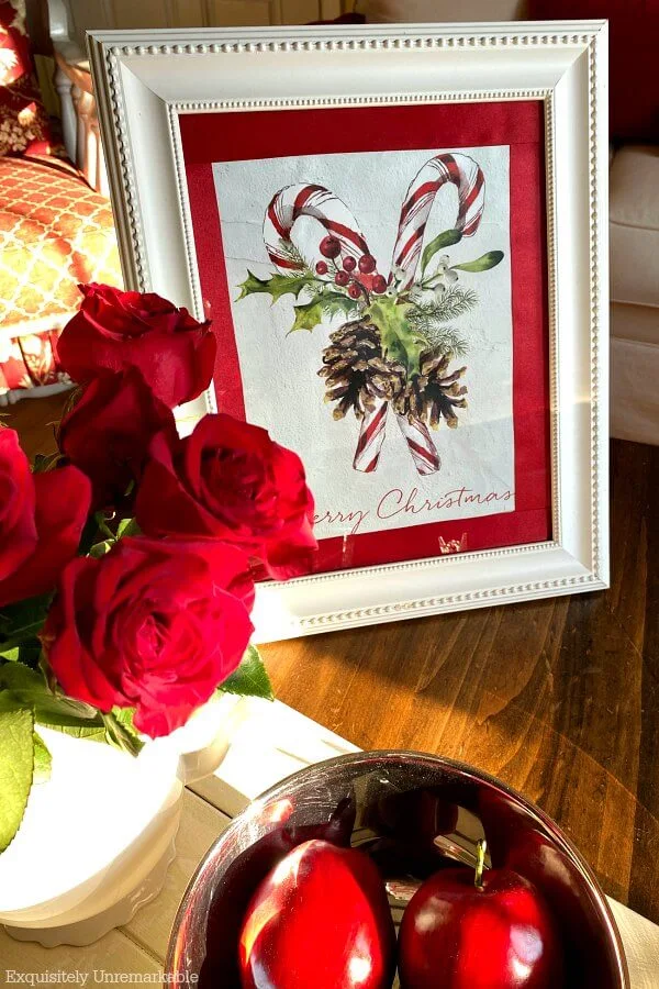 Framed candy cane gift bag on a table with red roses