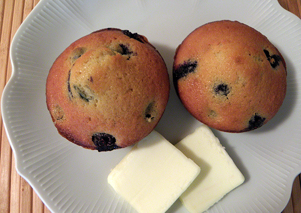 Two Blueberryy Muffins on a Plate with Two Pats of Butter