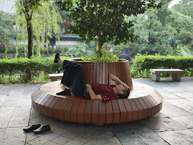 man sleeping on a circular bench at Liwan Park in Guangzhou