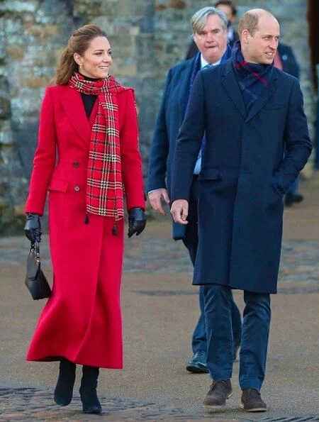 Kate Middleton wore a tartan pleated skirt from Emilia Wickstead, yellow gold hoops from Spells of Love. Alexander McQueen red coat. Grace Han bag