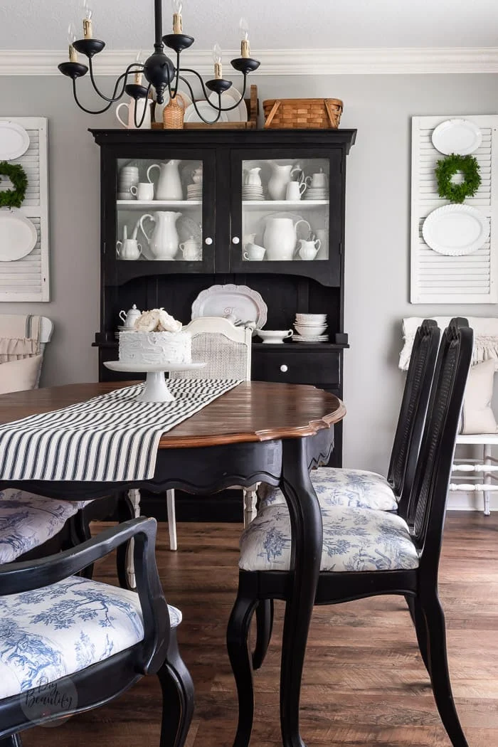 dining room with black hutch, white shutters, ironstone and striped table runner