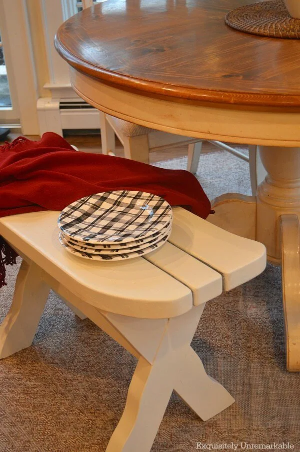 Curved white kitchen bench with plaid black dishes and a red throw
