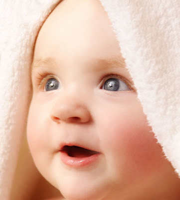 cute baby picture under white towel after bath smiling happily