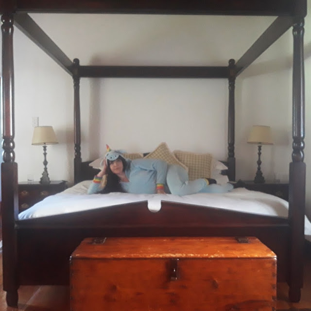 Girl in unicorn onesie on four-poster bed