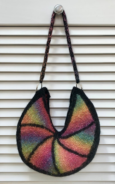 Felted bag knitted with rainbow colored and black yarn with icord handle