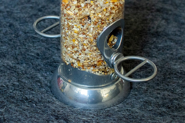 A close up of the end of a bird feeder for smaller birds with wild bird seed suitable for robins and tits