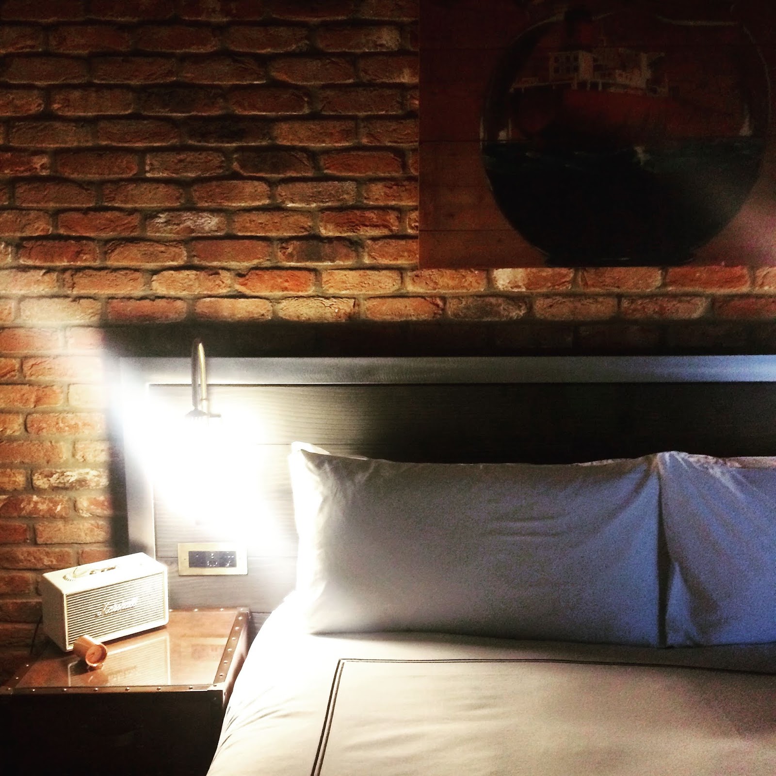 white bed with pillow against a brick wall at the the curtain hotel shoreditch