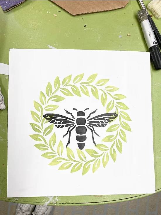 bee and wreath stenciled on a board for the frame
