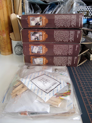 Pile of modern dolls' house miniature upholstery kits on a worktable, next to a bag with more kits in it.