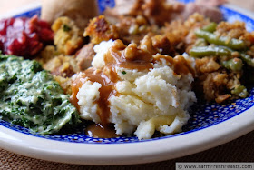 image of a traditional Thanksgiving plate of mashed potatoes, green beans, cranberry sauce, creamed spinach, stuffing, turkey and a roll