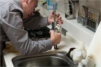 Man installing a new faucet in a kitchen.