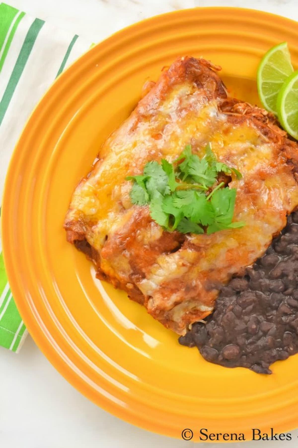 Chicken Enchiladas in Homemade Red Enchilada Sauce on a yellow plate served with refried black beans.