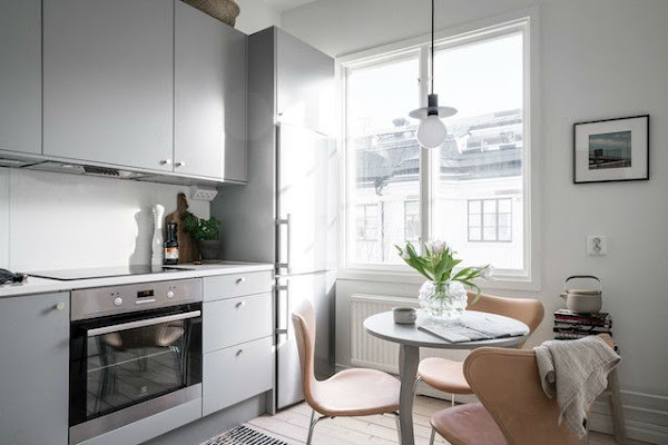 Cocina sencilla con mobiliario en gris y suelo de madera natural. Con pequeño office.