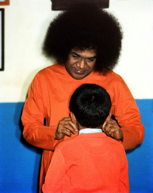 Sri Sathya Sai pulling the cheeks of a little boy