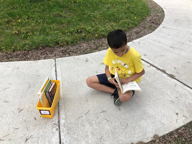 kid reading on sidewalk