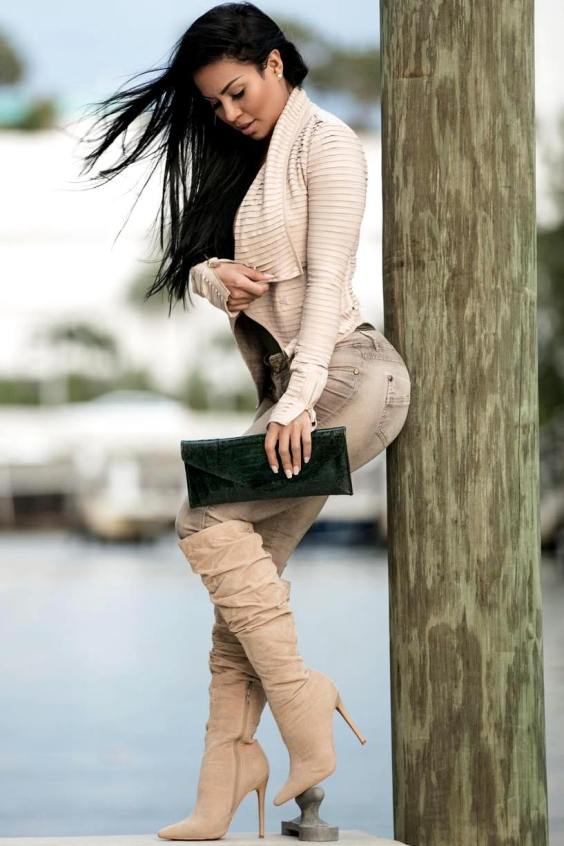 Woman wearing a beige sweater, brown jeans and beige over the knee boots