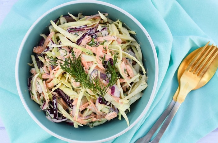 Vegan Coleslaw with Fresh Herbs in a pale blue bowl on a pale blue napkin, with gold cutlery