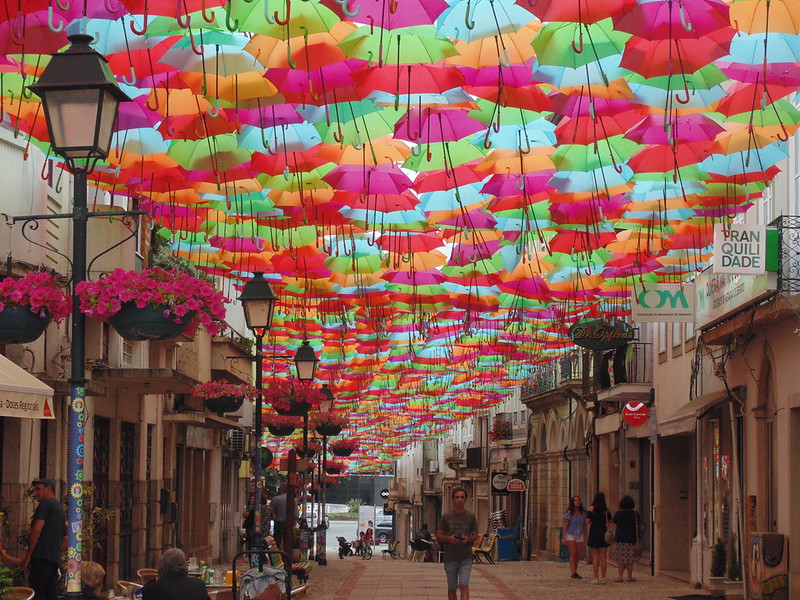 street of umbrellas, portugal umbrella sky, festival umbrella, colorful umbrella street, colorful umbrellas street, street with umbrellas, street covered with umbrellas,
