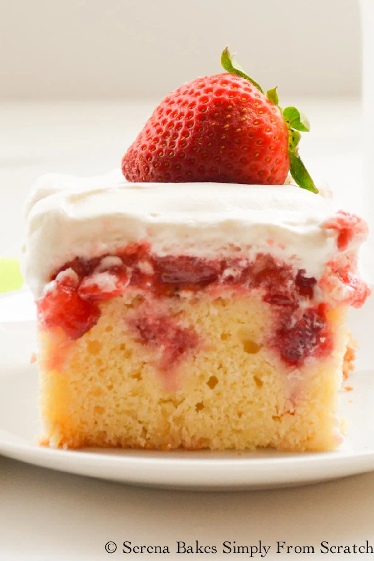 Strawberry Shortcake Poke Cake slice photo on a white plate.