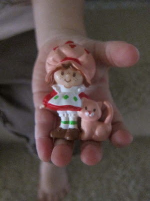 younger lass holding small Strawberry Shortcake figurine in her hand