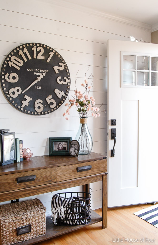 plank wall, large clock and spring flowers in the entryway