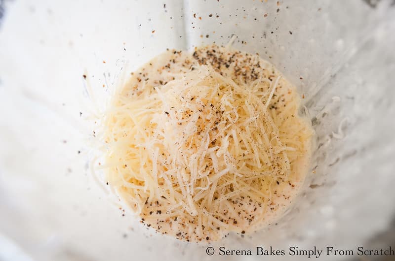 Creamy Ceasar Salad Dressing with Grated Parmesan Cheese and Black Pepper on top in a glass blender looking down.
