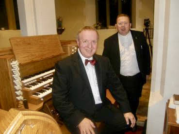 Nigel Ogden sitting at Wyvern 3 Manual just installed, with Rev. Quentin Bellamy. lit church at night