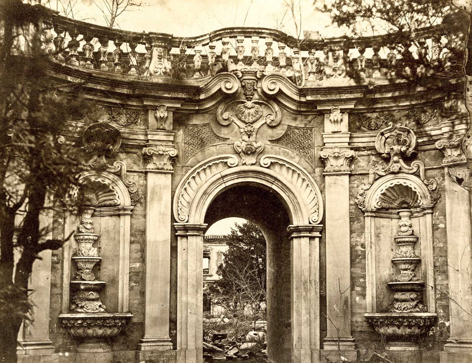A view of the Fountain Gate in Yuan Ming Yuan, or the Garden of Perfect Brightness. Beginning in 1709, the Qing emperor Kangxi began the construction of this garden retreat, which was modeled on the grand palaces, gardens, and fountains of Europe. Much of Yuan Ming Yuan was destroyed in the Second Opium War.