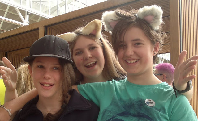 Three girls one with a peaked cap and two wearing hand-made fluffy cat ears.