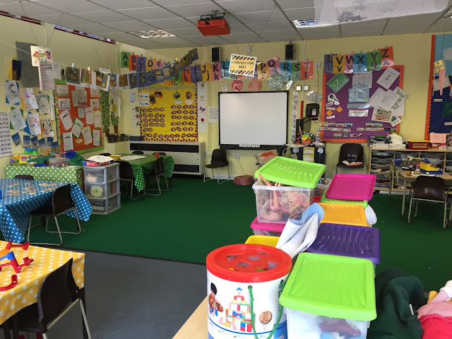 a reception school room with boxes of activities, tables and lots of things on the walls like alphabet and numbers