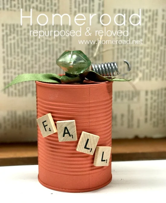 aluminum can pumpkin with scrabble letters and glass knob with newspaper background