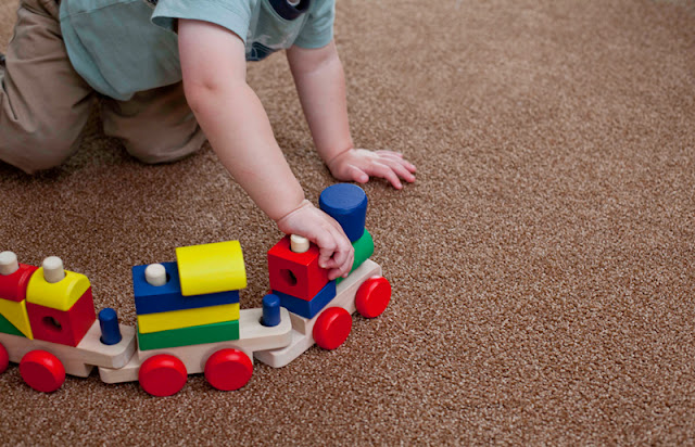 Child plays with a train on his carpeted bedroom floor