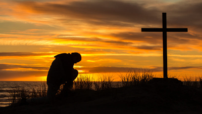 imagem de uma pessoa rezando diante da Cruz
