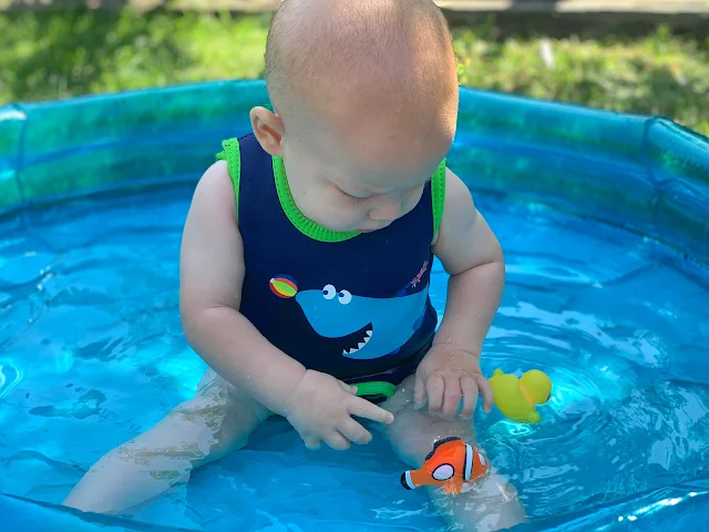 6 month old boy in a paddling pool playing with toys