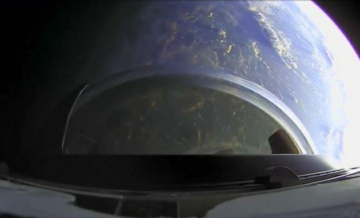 Space x shown from the sky where the earth is dark