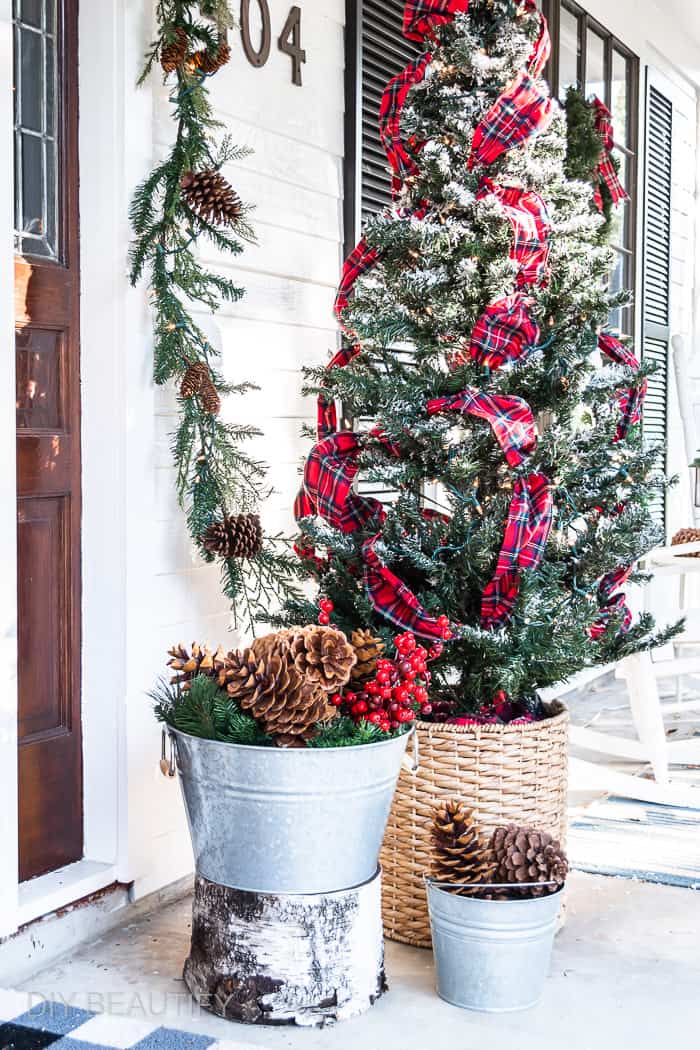 Christmas tree on porch and galvanized buckets filled with sugar pine cones