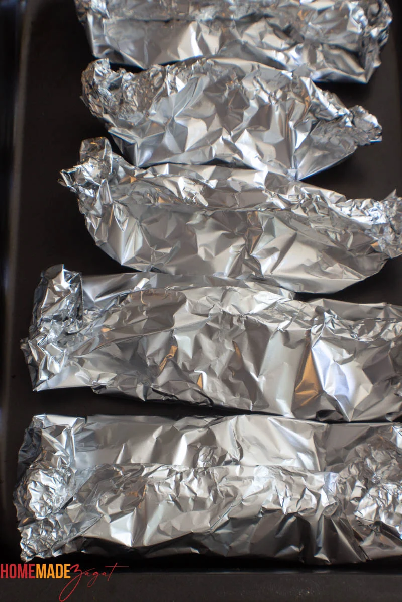 Wrapped foil packets ready to be baked in a baking tray