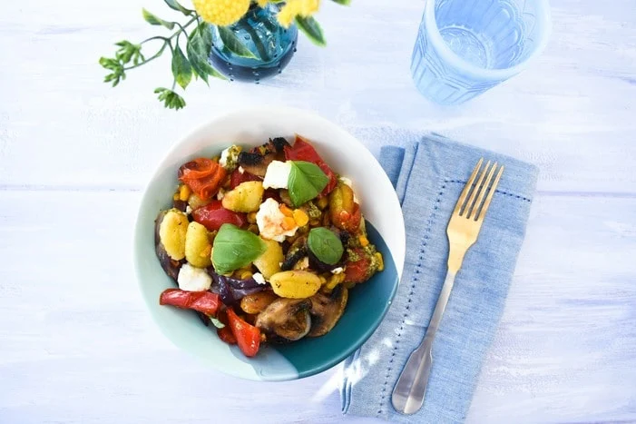 Roasted Vegetable Gnocchi Bake served in a pale blue with a blue napkin and fork