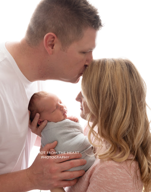 mom and dad with newborn on white background