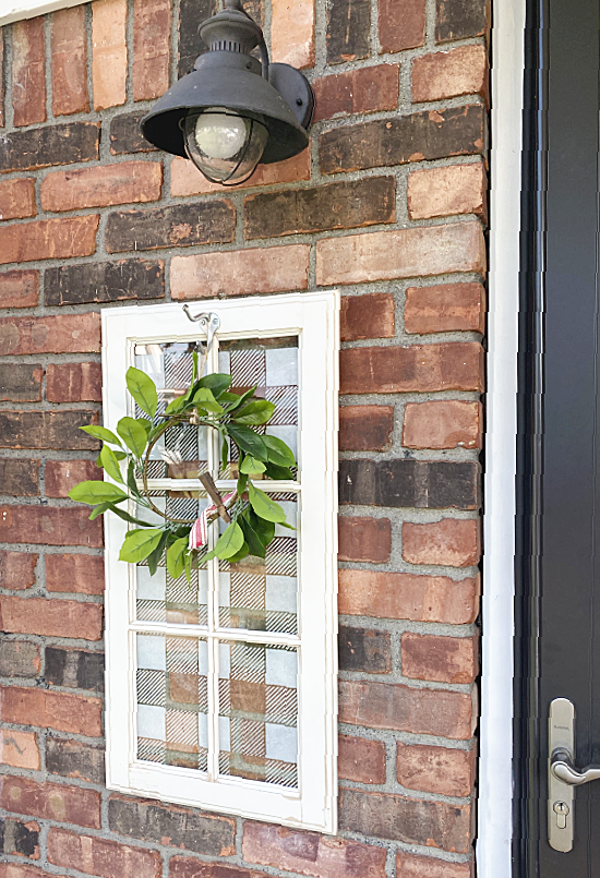 stenciled window with a wreath outdoor on brick